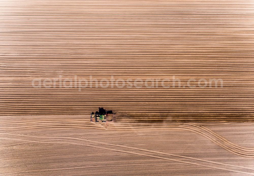 Wittenbeck from the bird's eye view: Plowing and shifting the earth by a tractor with plow on agricultural fields in Wittenbeck in the state Mecklenburg - Western Pomerania, Germany
