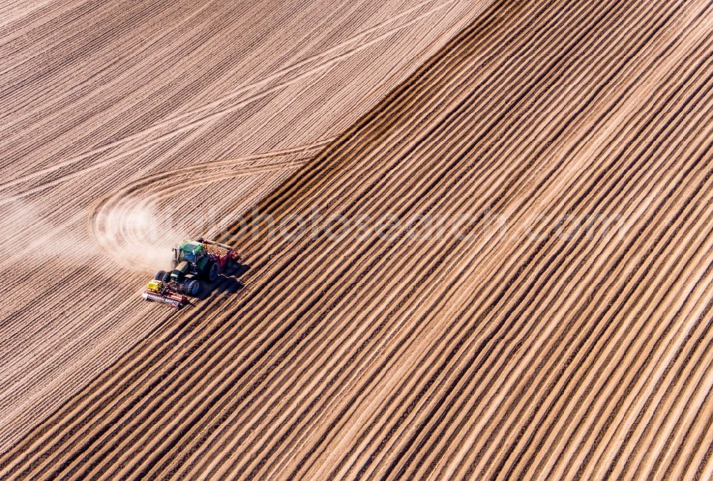 Aerial image Wittenbeck - Plowing and shifting the earth by a tractor with plow on agricultural fields in Wittenbeck in the state Mecklenburg - Western Pomerania, Germany