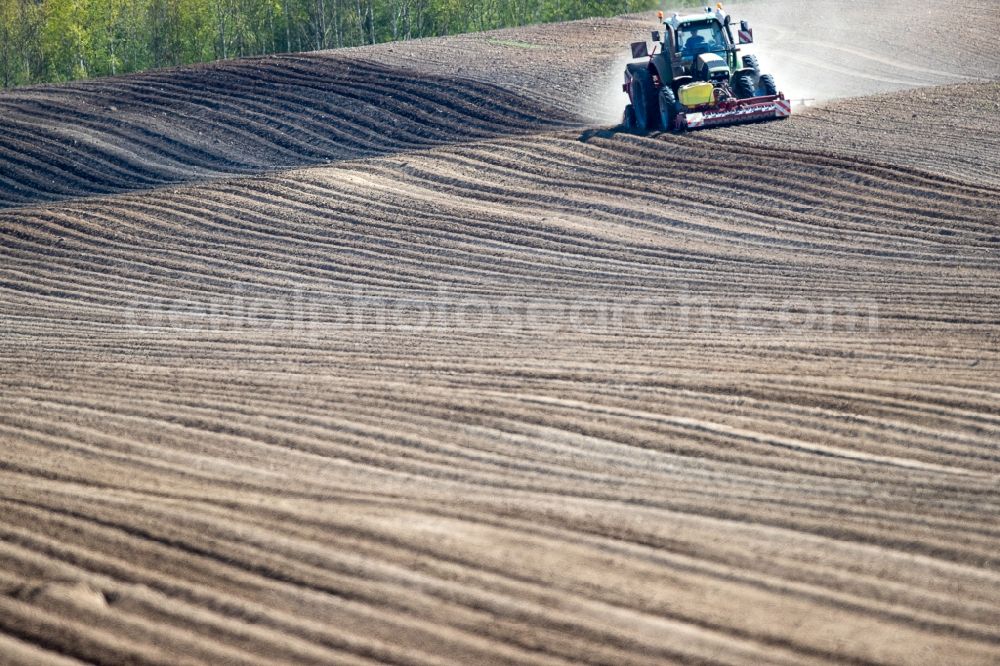 Wittenbeck from above - Plowing and shifting the earth by a tractor with plow on agricultural fields in Wittenbeck in the state Mecklenburg - Western Pomerania, Germany