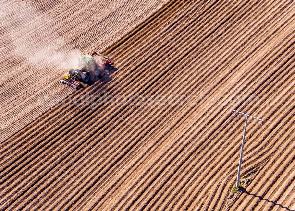 Wittenbeck from the bird's eye view: Plowing and shifting the earth by a tractor with plow on agricultural fields in Wittenbeck in the state Mecklenburg - Western Pomerania, Germany