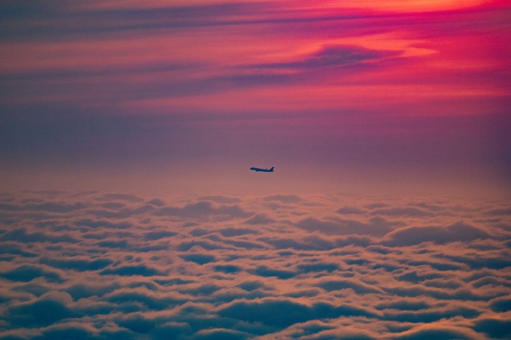 Norderstedt from the bird's eye view: Airliner in the sunrise over the clouds after take-off in Hamburg Fuhlsbuettel in the height of Norderstedt in the state Schleswig-Holstein Germany