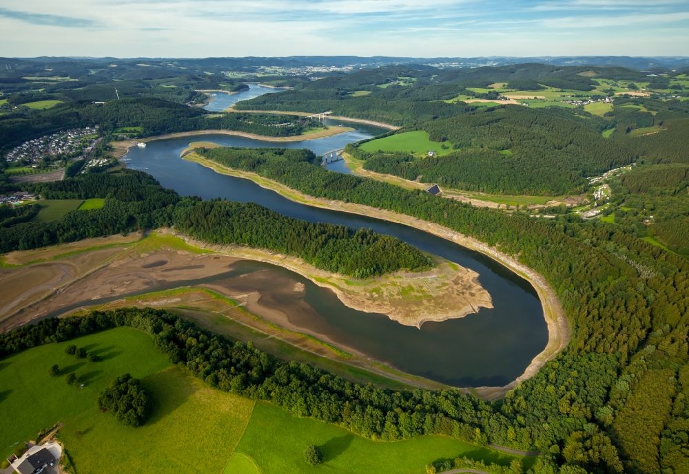 Olpe from above - Dam and shore areas at the lake Biggetalsperre in Olpe in the state North Rhine-Westphalia. A lowered water level allows repair works at the dam near the Eichhagen part of the town