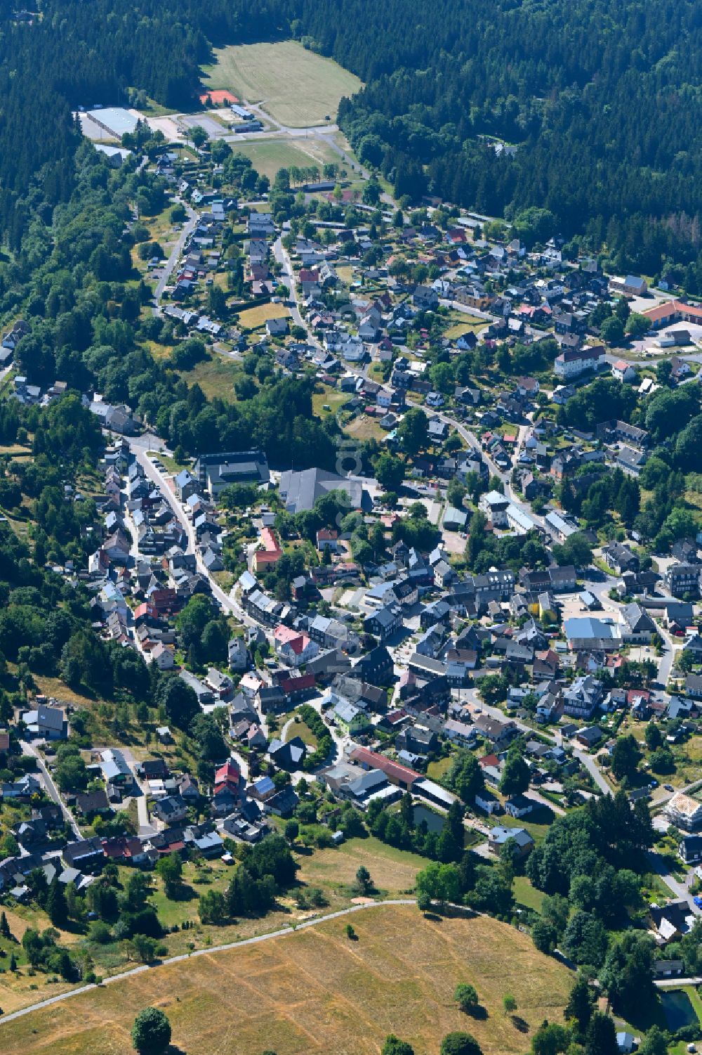 Schmiedefeld am Rennsteig from the bird's eye view: Surrounded by forest and forest areas center of the streets and houses and residential areas in Schmiedefeld am Rennsteig in the state Thuringia, Germany