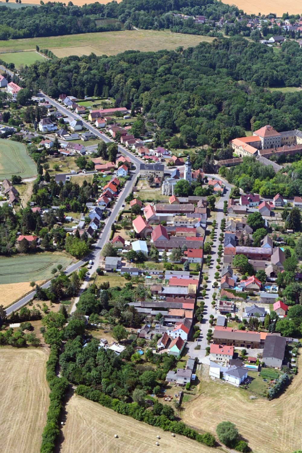 Aerial photograph Wölkau - Surrounded by forest and forest areas center of the streets and houses and residential areas in Woelkau in the state Saxony, Germany