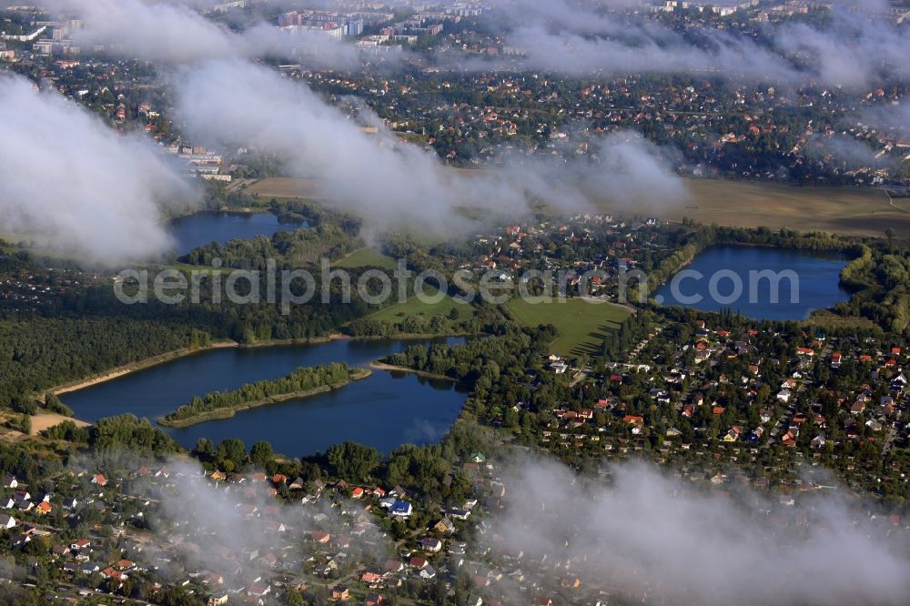 Aerial photograph Berlin - View of clouds circling the countryside surrounding the three Kaulsdorfer Lakes Butzer See, Elsensee and Habermannsee in Berlin - Kaulsdorf. The lakes are located in a nature preserve surrounded by localities with small houses