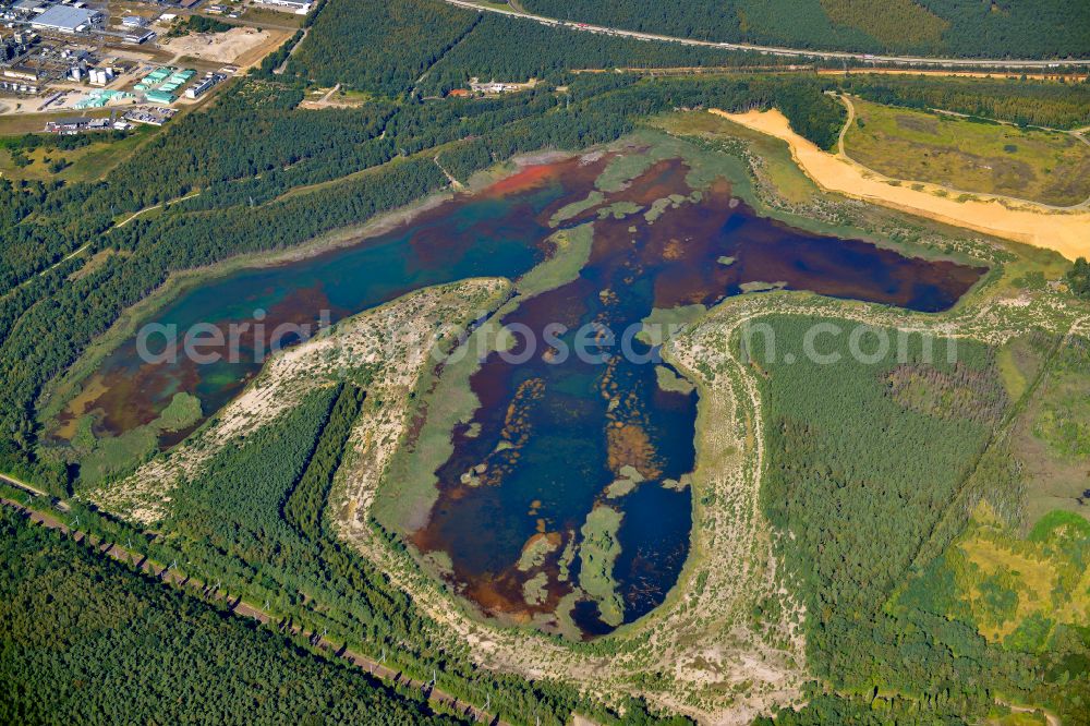 Kolonie Fortschritt from the bird's eye view: Colorful water surface and water discoloration in open-cast mining, overburden and residual areas due to sulfuric acid compounds and oxidized iron compounds These are dissolved by rising groundwater and lead to acidification and clogging of the water. in Kolonie Fortschritt in the state Brandenburg, Germany