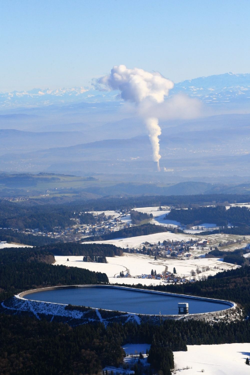 Aerial image Herrischried - In winter snowy landscape on the Hotzenwald in Herrischried in the state of Baden-Wuerttemberg, the Hornbergbecken is the high reservoir of the pumped storage hydro power station of the Schluchseewerk AG. In the background, the plume of nuclear power plant Leibstadt in Switzerland