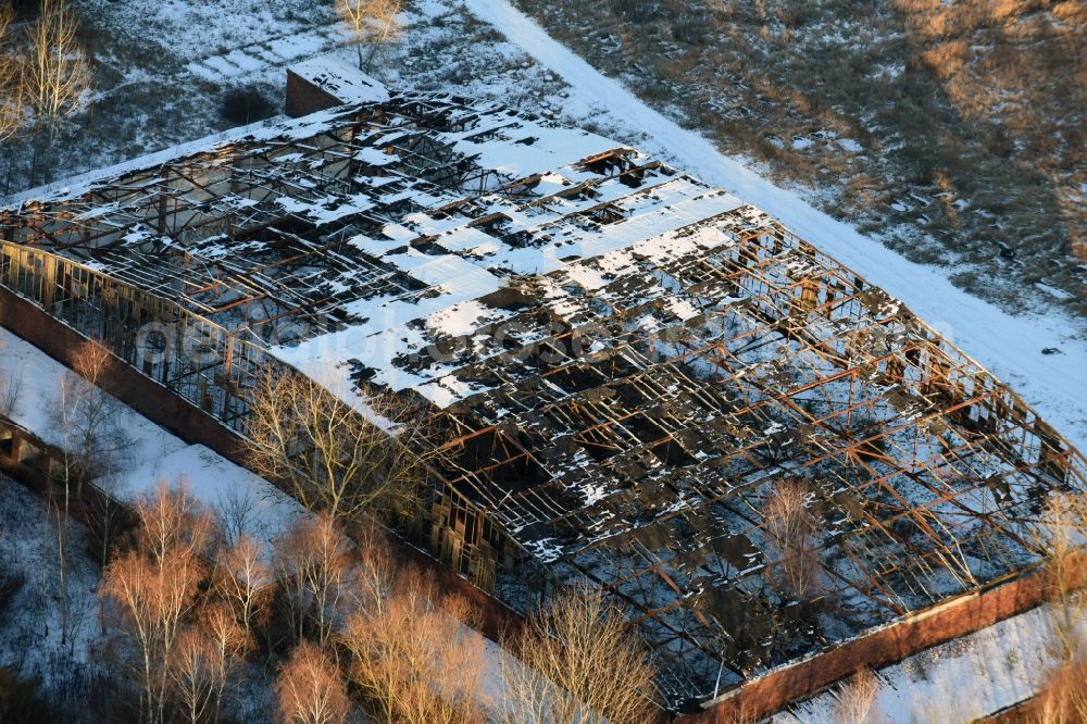 Aerial image Oberkrämer - Wintery snow- covered roof holes in the ruins of the former airfield hangars on the abandoned military airfield in Schoenwalde in Brandenburg