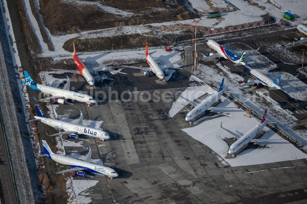 Aerial image Hamburg - Wintry snowy due to the pandemic, new aircraft A320 - A321 in the respective customer liveries parked in the open spaces and parking positions in the Airbus SE shipyard premises in the Finkenwerder district in Hamburg, Germany