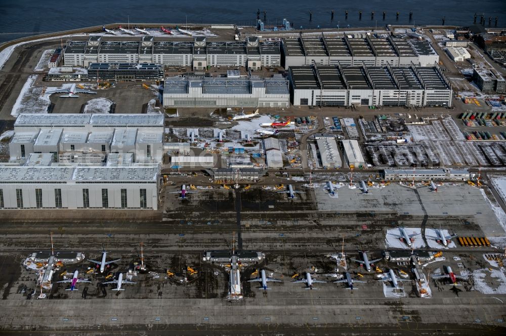 Hamburg from the bird's eye view: Wintry snowy due to the pandemic, new aircraft A320 - A321 in the respective customer liveries parked in the open spaces and parking positions in the Airbus SE shipyard premises in the Finkenwerder district in Hamburg, Germany