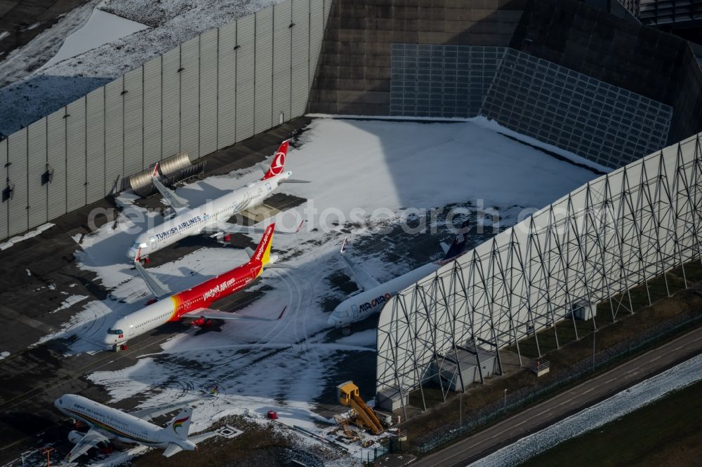 Hamburg from above - Wintry snowy due to the pandemic, new aircraft A320 - A321 in the respective customer liveries parked in the open spaces and parking positions in the Airbus SE shipyard premises in the Finkenwerder district in Hamburg, Germany