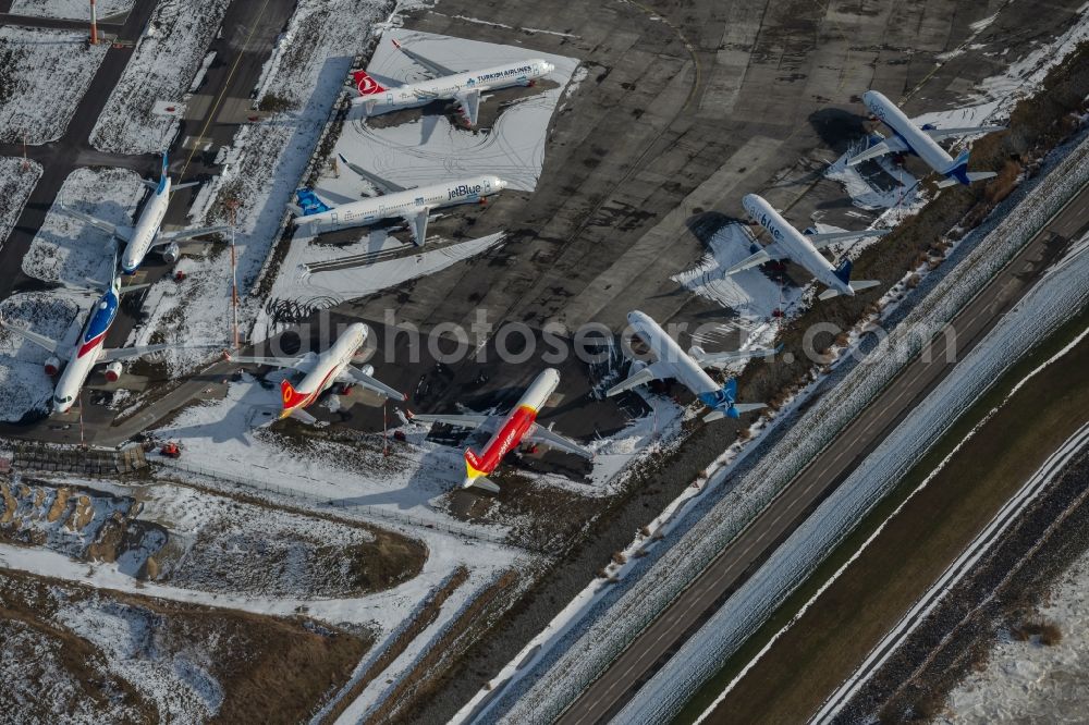 Aerial photograph Hamburg - Wintry snowy due to the pandemic, new aircraft A320 - A321 in the respective customer liveries parked in the open spaces and parking positions in the Airbus SE shipyard premises in the Finkenwerder district in Hamburg, Germany