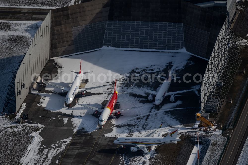 Hamburg from above - Wintry snowy due to the pandemic, new aircraft A320 - A321 in the respective customer liveries parked in the open spaces and parking positions in the Airbus SE shipyard premises in the Finkenwerder district in Hamburg, Germany
