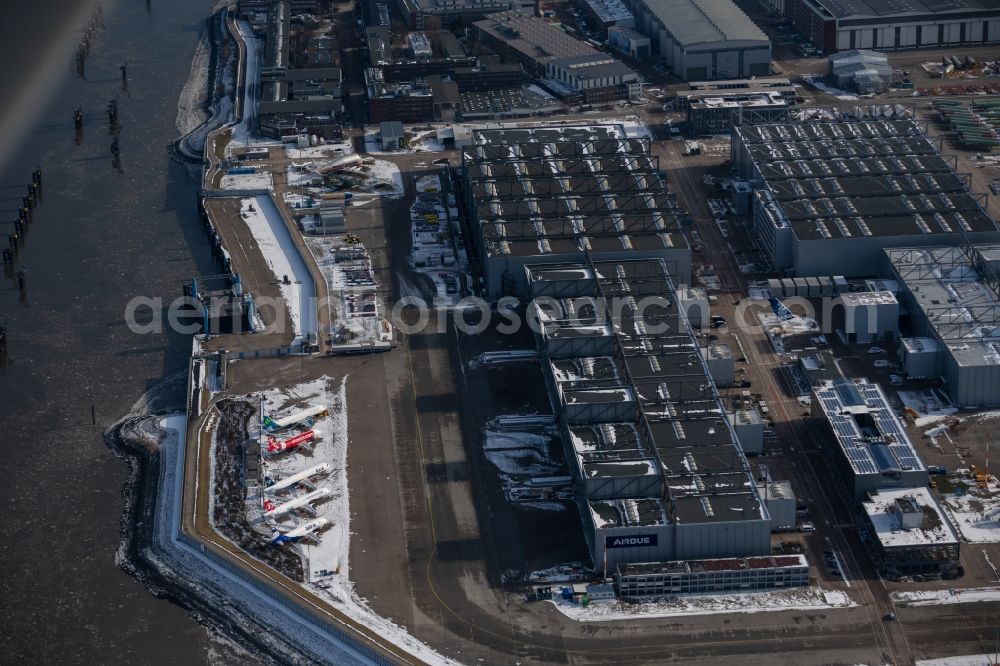 Hamburg from the bird's eye view: Wintry snowy due to the pandemic, new aircraft A320 - A321 in the respective customer liveries parked in the open spaces and parking positions in the Airbus SE shipyard premises in the Finkenwerder district in Hamburg, Germany