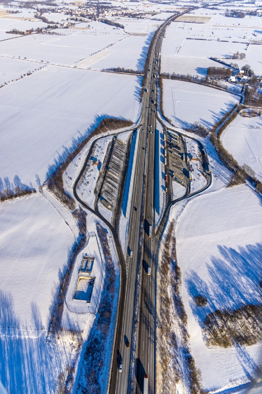 Röllingsen from above - Wintry snowy motorway parking lot and parking area for automobiles with rest area and toilet for short stays on the edge of the course of the BAB A 44 - Roellingser Graben and Ostoenner Grand in Roellingsen at Ruhrgebiet in the state North Rhine-Westphalia, Germany