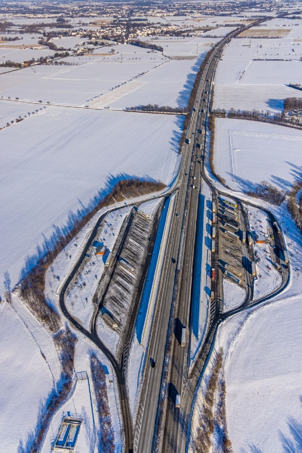 Röllingsen from the bird's eye view: Wintry snowy motorway parking lot and parking area for automobiles with rest area and toilet for short stays on the edge of the course of the BAB A 44 - Roellingser Graben and Ostoenner Grand in Roellingsen at Ruhrgebiet in the state North Rhine-Westphalia, Germany
