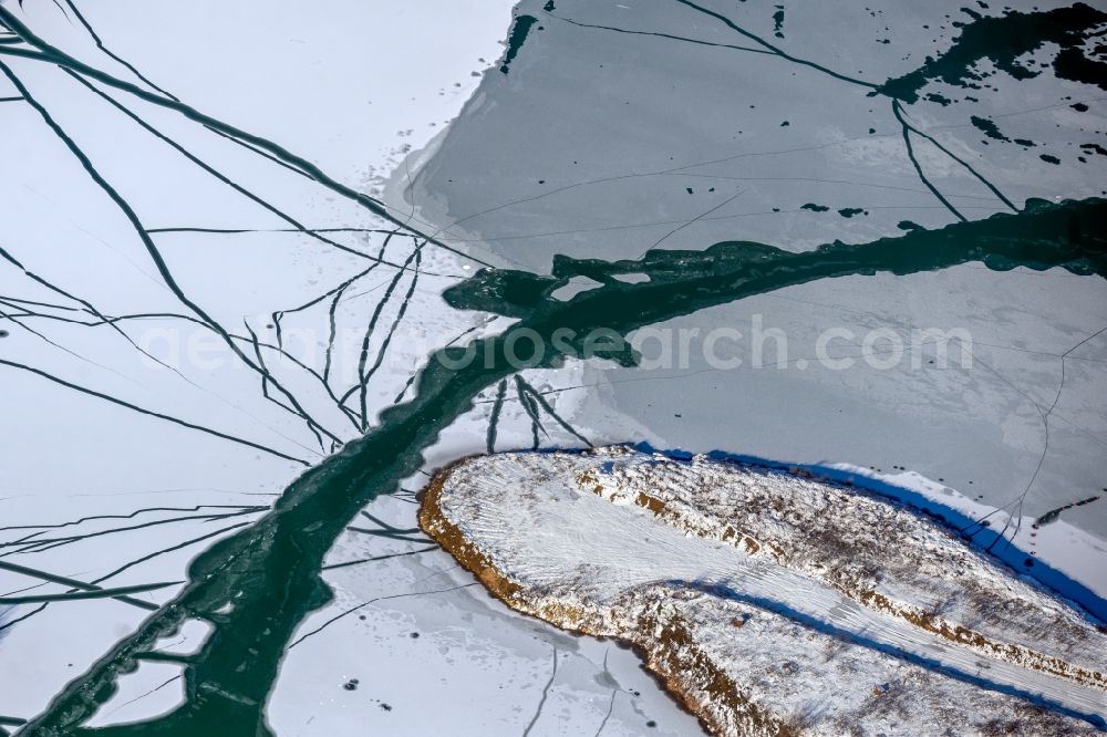 Aerial image Dettelbach - Wintry snowy lake shore and overburden areas of the quarry lake and gravel open pit Dettelbacher Baggersee in Dettelbach in the state Bavaria, Germany