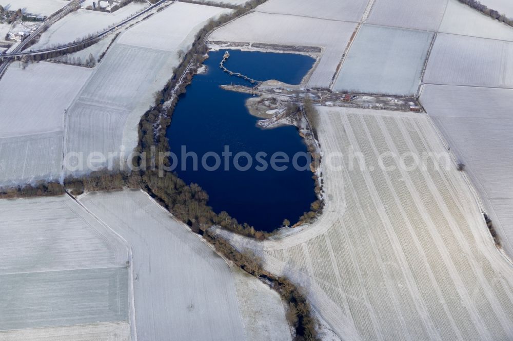 Aerial photograph Friedland - Wintry snowy lake shore and overburden areas of the quarry lake and gravel open pit in Friedland in the state Lower Saxony, Germany