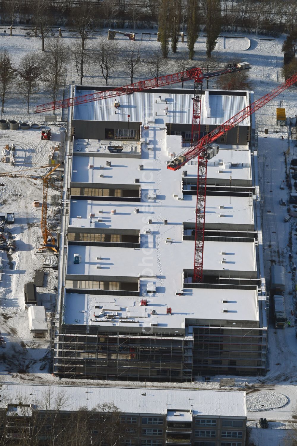 Berlin from the bird's eye view: Wintry snowy new construction site of the school building Gymnasium with Sporthalle on street Erich-Kaestner-Strasse - Peter-Huchel-Strasse in the district Hellersdorf in Berlin, Germany