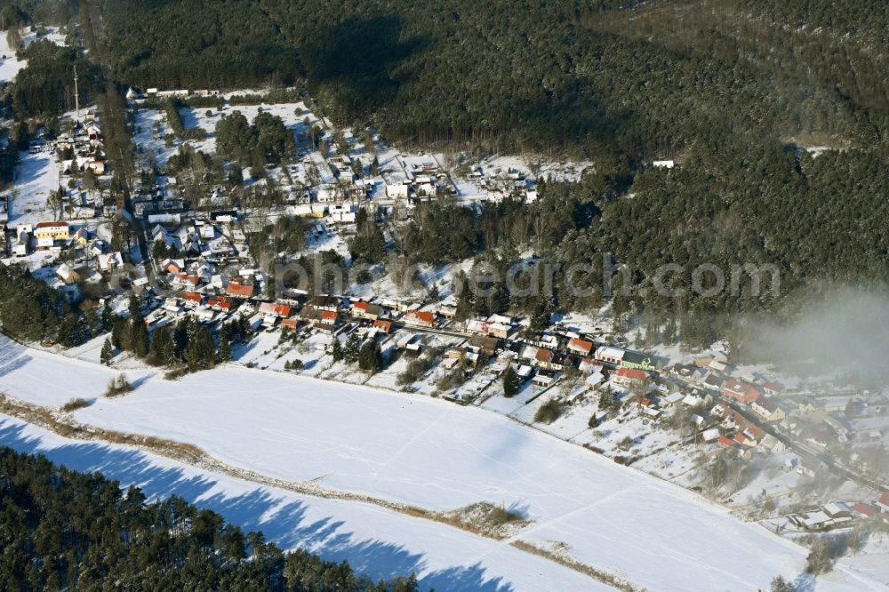 Groß Dölln from the bird's eye view: Wintry snowy village - view on the edge of forested areas in Gross Doelln in the state Brandenburg, Germany