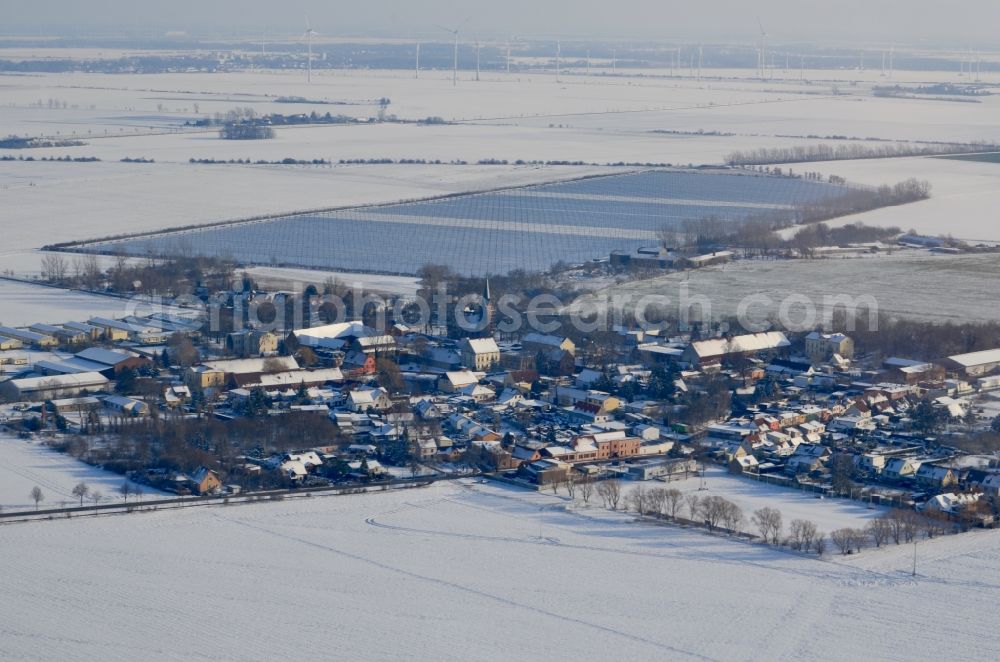 Baasdorf from the bird's eye view: Wintry snowy agricultural land and field boundaries surround the settlement area of the village in Baasdorf in the state Saxony-Anhalt, Germany