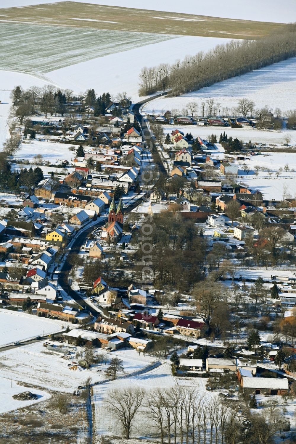 Willmersdorf from the bird's eye view: Wintry snowy agricultural land and field boundaries surround the settlement area of the village in Willmersdorf in the state Brandenburg, Germany