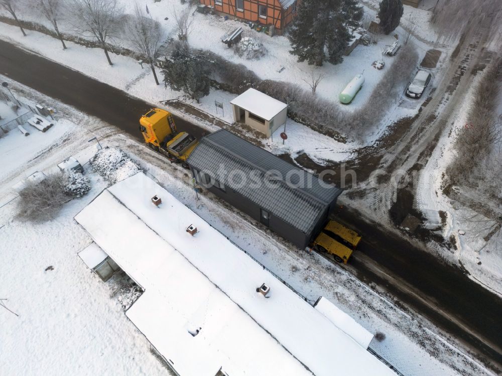 Groß Daberkow from above - Wintry snowy single-family house - delivery as a chalet - tiny house with a heavy load transport on the road to the pastor's house in Gross Daberkow in the state Mecklenburg-Western Pomerania, Germany