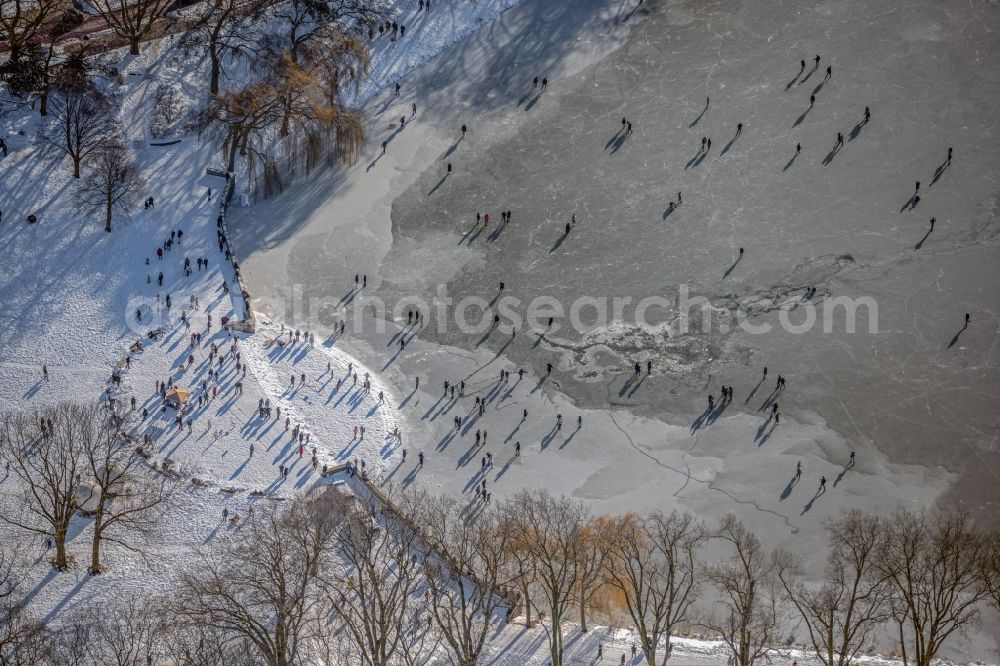 Aerial photograph Münster - Wintry snowy strollers and passers-by walk on the ice sheet of the frozen bank areas of the lake - surface of Aasee in the district Pluggendorf in Muenster in the state North Rhine-Westphalia, Germany