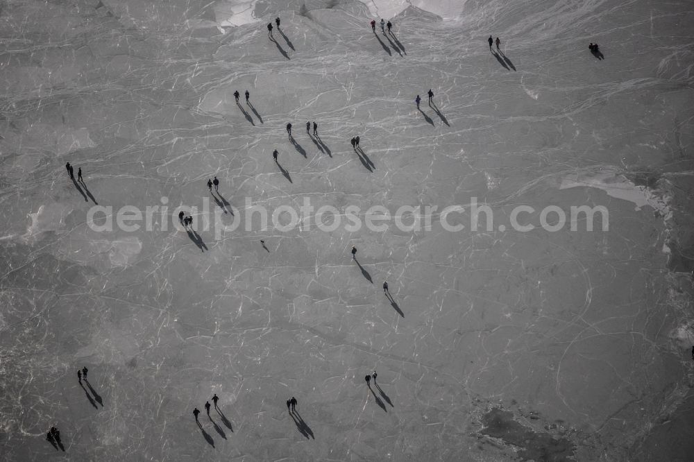Münster from above - Wintry snowy strollers and passers-by walk on the ice sheet of the frozen bank areas of the lake - surface of Aasee in the district Pluggendorf in Muenster in the state North Rhine-Westphalia, Germany