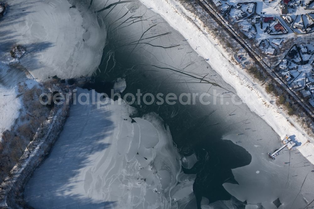Aerial image Dankern - Wintry snowy strollers and passers-by walk on the ice sheet of the frozen bank areas of the lake - surface of Dankernsee in Dankern in the state Lower Saxony, Germany
