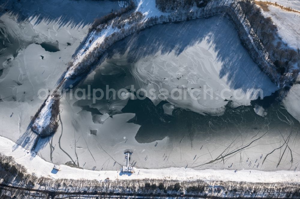 Dankern from the bird's eye view: Wintry snowy strollers and passers-by walk on the ice sheet of the frozen bank areas of the lake - surface of Dankernsee in Dankern in the state Lower Saxony, Germany