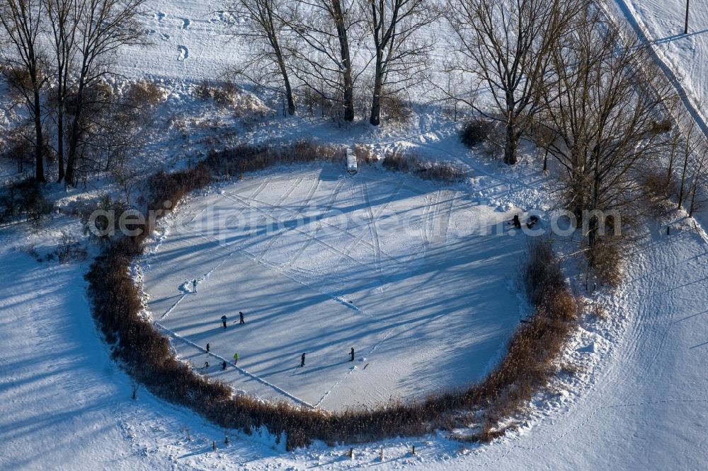 Südharz from above - Wintry snowy strollers and passers-by walk on the ice sheet of the frozen bank areas of the lake - surface Der kleine See with ice hockey players in the district Uftrungen in Suedharz in the state Saxony-Anhalt, Germany