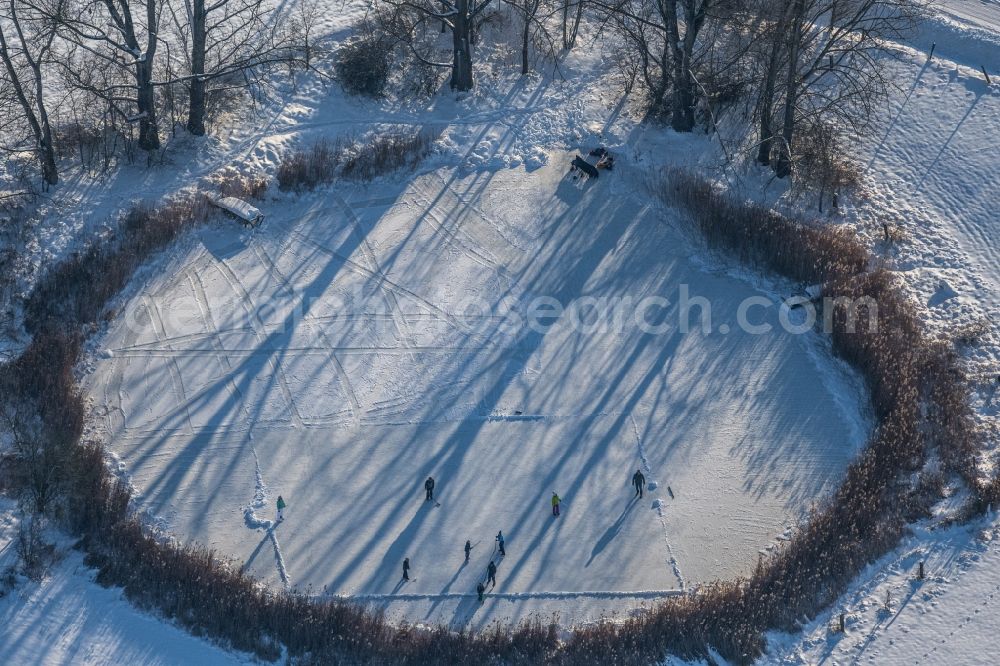 Südharz from the bird's eye view: Wintry snowy strollers and passers-by walk on the ice sheet of the frozen bank areas of the lake - surface Der kleine See with ice hockey players in the district Uftrungen in Suedharz in the state Saxony-Anhalt, Germany