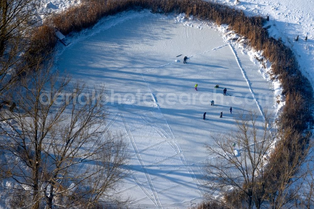 Aerial image Südharz - Wintry snowy strollers and passers-by walk on the ice sheet of the frozen bank areas of the lake - surface Der kleine See with ice hockey players in the district Uftrungen in Suedharz in the state Saxony-Anhalt, Germany