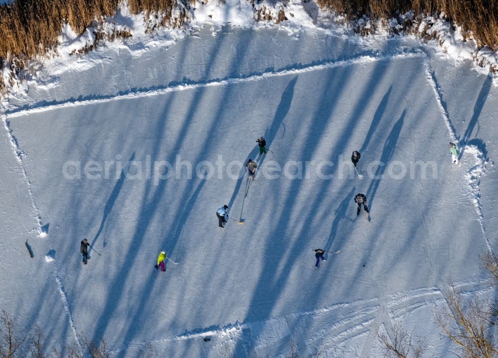 Aerial photograph Südharz - Wintry snowy strollers and passers-by walk on the ice sheet of the frozen bank areas of the lake - surface Der kleine See with ice hockey players in the district Uftrungen in Suedharz in the state Saxony-Anhalt, Germany