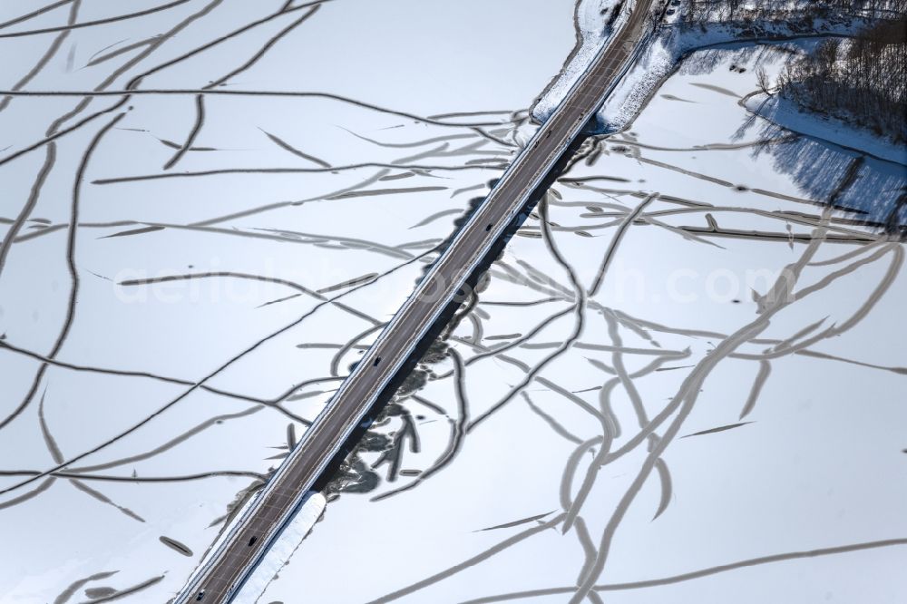 Möhnesee from the bird's eye view: Wintry snowy river - bridge construction der Delecker Bruecke along the Arnsberger Strasse in Moehnesee in the state North Rhine-Westphalia, Germany