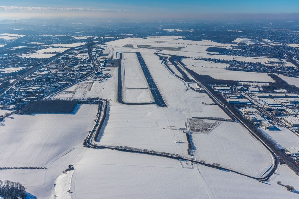 Dortmund from the bird's eye view: Wintry snowy runway with hangar taxiways and terminals on the grounds of the airport in Dortmund in the state North Rhine-Westphalia, Germany