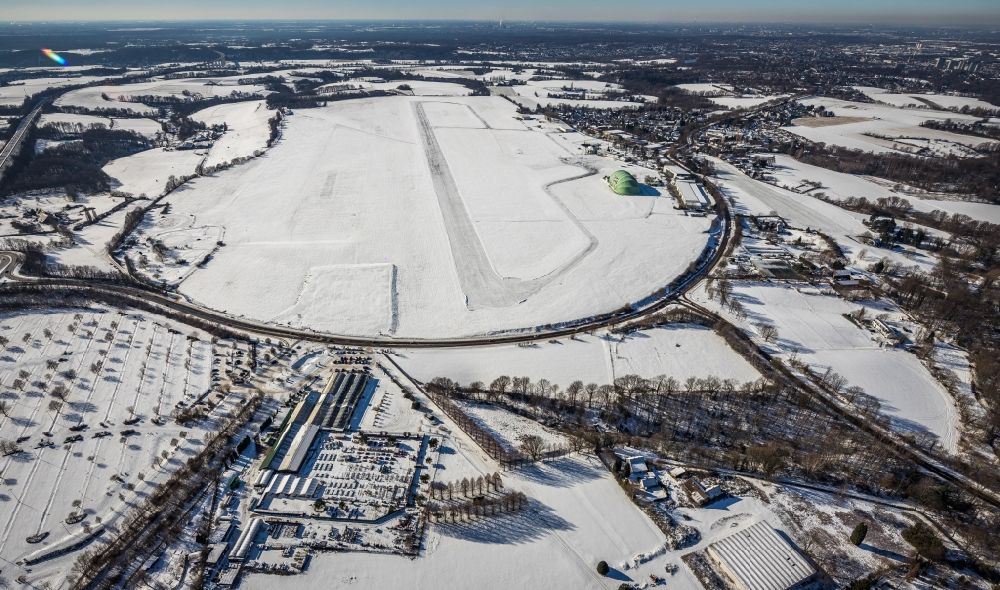 Aerial photograph Mülheim an der Ruhr - Wintry snowy runway with hangar taxiways and terminals on the grounds of the airport in the district Flughafensiedlung in Muelheim on the Ruhr in the state North Rhine-Westphalia