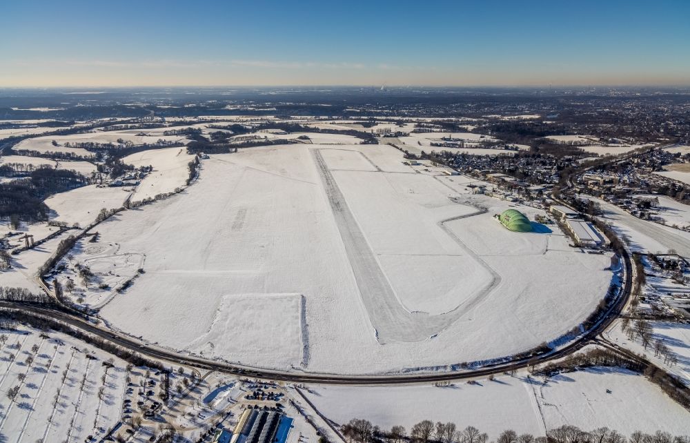 Mülheim an der Ruhr from the bird's eye view: Wintry snowy runway with hangar taxiways and terminals on the grounds of the airport in the district Flughafensiedlung in Muelheim on the Ruhr in the state North Rhine-Westphalia