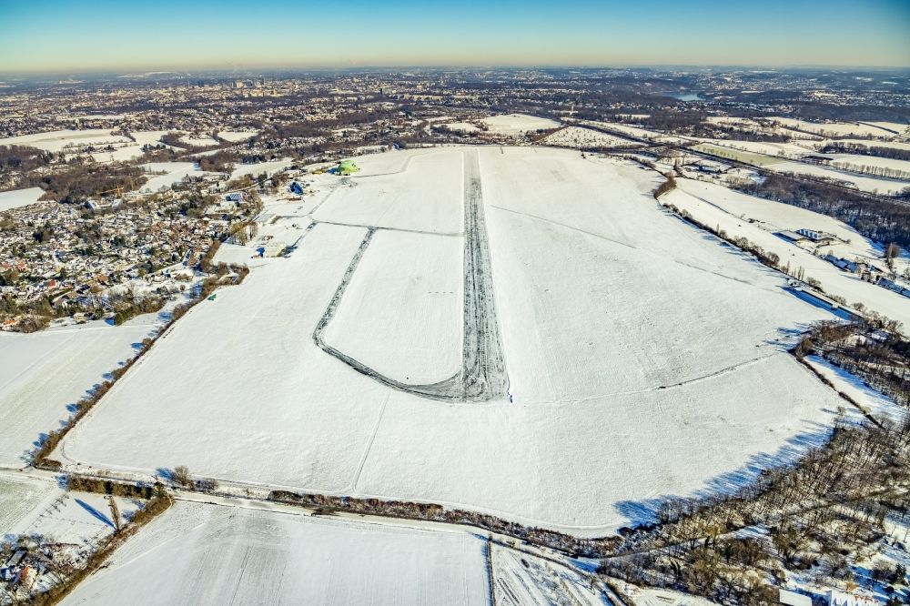 Mülheim an der Ruhr from above - Wintry snowy runway with hangar taxiways and terminals on the grounds of the airport in the district Flughafensiedlung in Muelheim on the Ruhr at Ruhrgebiet in the state North Rhine-Westphalia