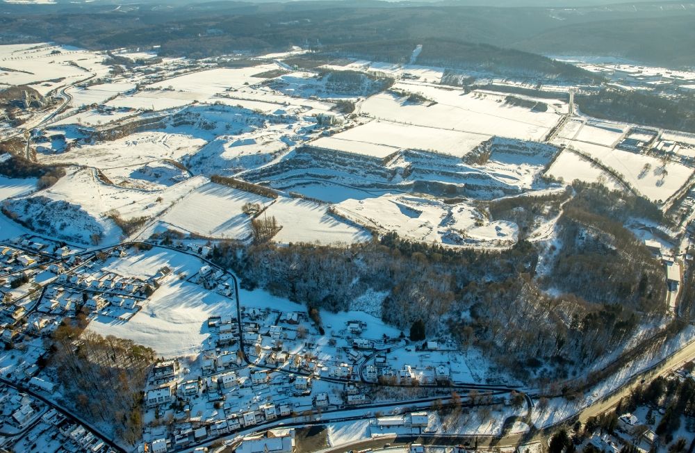 Warstein from the bird's eye view: Wintry snowy Terrain and overburden surfaces of the chalk mine open pit of the Calcis Warstein GmbH & Co. KG in Warstein in the state North Rhine-Westphalia