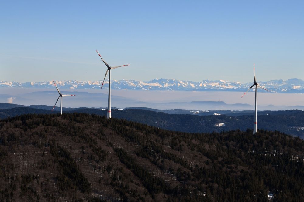 Schopfheim from above - Wintry snowy landscape at the snow covered Rohrenkopf, the local mountain of Gersbach, a district of Schopfheim in Baden-Wuerttemberg. Wind turbines produce renewable energy in the wind farm. Looking over the mountains of the Black Forest to the Swiss Alps