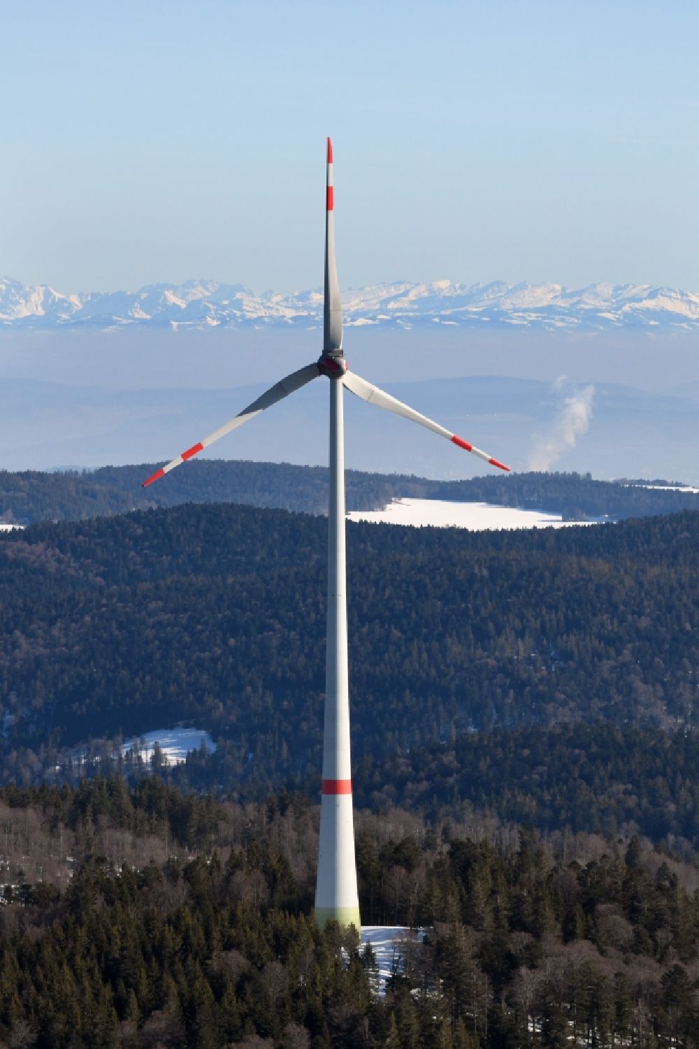Aerial photograph Schopfheim - Wintry snowy landscape at the snow covered Rohrenkopf, the local mountain of Gersbach, a district of Schopfheim in Baden-Wuerttemberg. Wind turbines produce renewable energy in the wind farm. Looking over the mountains of the Black Forest to the Swiss Alps