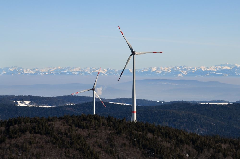 Schopfheim from the bird's eye view: Wintry snowy landscape at the snow covered Rohrenkopf, the local mountain of Gersbach, a district of Schopfheim in Baden-Wuerttemberg. Wind turbines produce renewable energy in the wind farm. Looking over the mountains of the Black Forest to the Swiss Alps