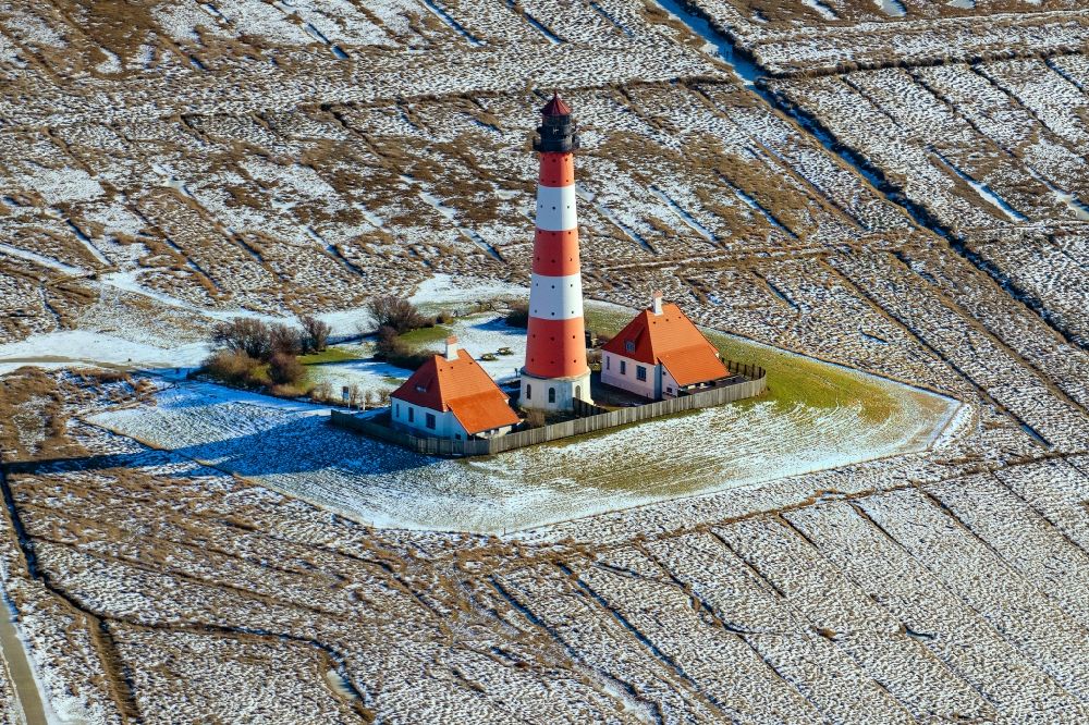 Tating from above - Wintry snowy lighthouse as a historic seafaring character in the coastal area of North Sea in the district Hauert in Westerhever in the state Schleswig-Holstein