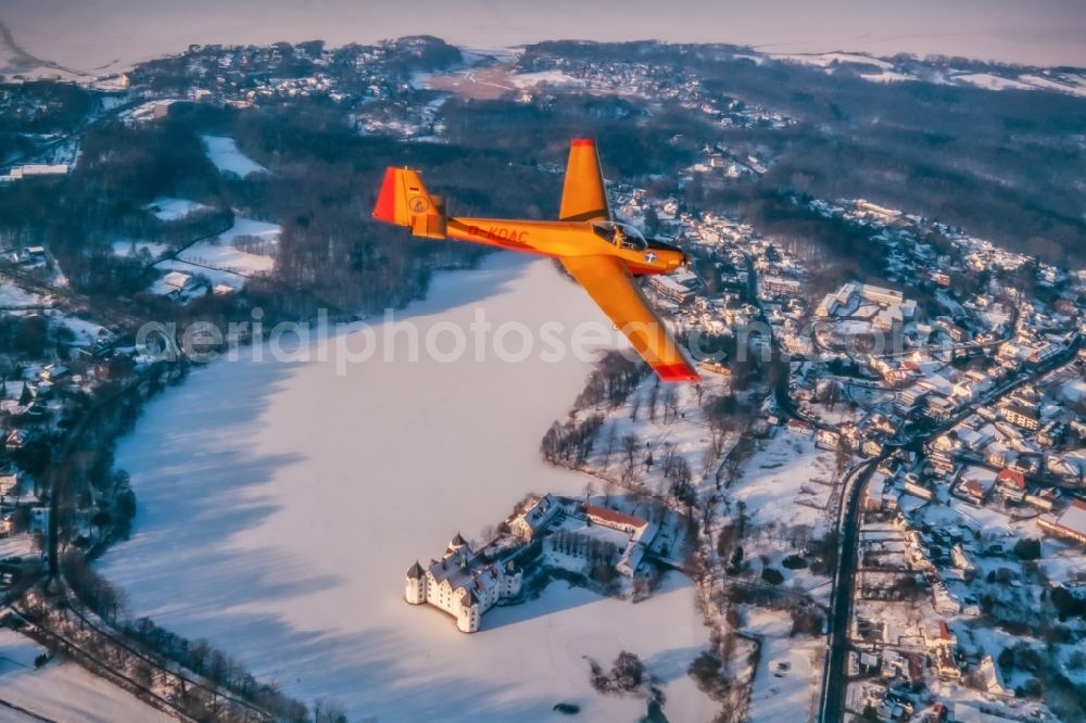 Glücksburg from above - Winter aerial photograph of the motor glider Scheibe SF 25 Falke with the registration D-KDAC in flight over the airspace in Glucksburg in the state Schleswig-Holstein, Germany. Airplane over the icy and snowy landscape at the Flensburg Fjord