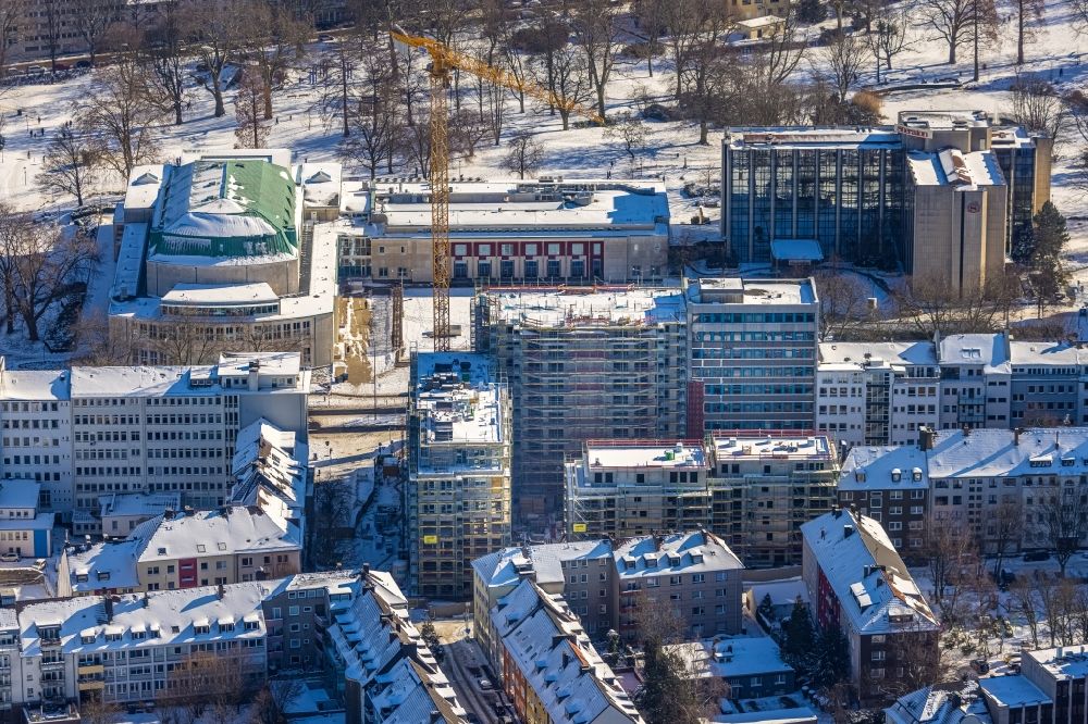 Essen from the bird's eye view: Wintry snowy construction site to build a new residential and commercial building HQE Huyssen Quartier Essen with residential tower and senior citizens' apartments on Huyssenallee - corner of Heinrichstrasse in Essen in the Ruhr area in the state North Rhine-Westphalia, Germany