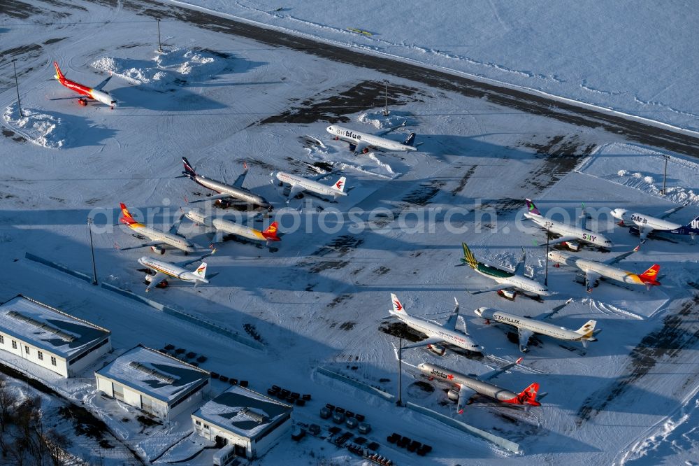 Aerial image Erfurt - Brand-new passenger aircrafts of the type Airbus A321neo and A320neo covered in snow in winter before delivery to the parking position caused by the pandemic - parking area and alternative parking space at the Erfurt Weimar airport in the Bindersleben district of Erfurt in the state Thuringia, Germany