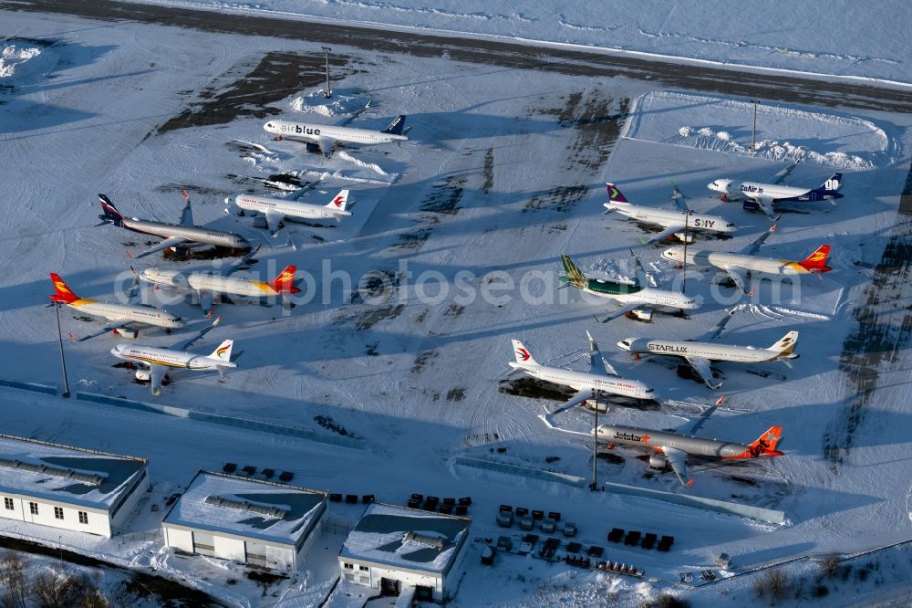 Aerial photograph Erfurt - Brand-new passenger aircrafts of the type Airbus A321neo and A320neo covered in snow in winter before delivery to the parking position caused by the pandemic - parking area and alternative parking space at the Erfurt Weimar airport in the Bindersleben district of Erfurt in the state Thuringia, Germany