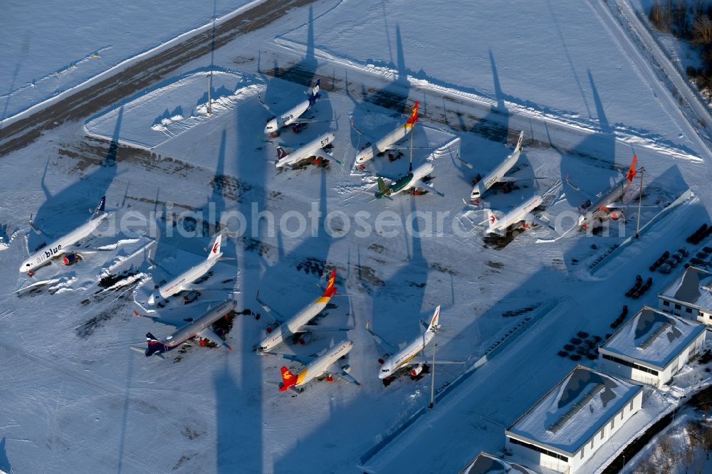 Erfurt from the bird's eye view: Brand-new passenger aircrafts of the type Airbus A321neo and A320neo covered in snow in winter before delivery to the parking position caused by the pandemic - parking area and alternative parking space at the Erfurt Weimar airport in the Bindersleben district of Erfurt in the state Thuringia, Germany